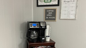 Angolo caffè con macchina da caffè, montalatte e tazza. In evidenza, sulla parete, due insegne: una con la scritta "Central Perk" e un'altra raffigurante una tazza di caffè.