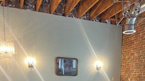 A neatly made bed in a room with a brick wall and wooden beams. There are wall sconces and a small table with a lamp. - Historic Luxury on Main Street in Spring Hill (Spring Hill)