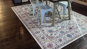 A dining area with a wooden table, white chairs, and a patterned rug. - Historic Luxury on Main Street in Spring Hill (Spring Hill)