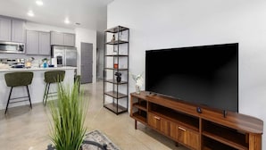 Eine moderne Küche mit grauen Schränken, einem Edelstahlkühlschrank und einer Bar mit zwei Barhocker.