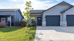 Ein modernes, zweistöckiges Haus mit Garage, einem gepflegten Rasen und blauem Himmel.