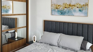 Camera da letto moderna con un letto, comodino, specchio e un'opera d'arte appesa al muro.
