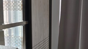 Una stanza con una finestra, una tenda e un tavolo con tovaglia a quadri.