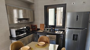 Una cucina moderna con un tavolo da pranzo per quattro persone, un frigorifero e una finestra sopra il lavello.