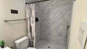 Een badkamer met toilet, douche en handdoekhouder.