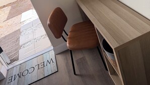 Een moderne kantoorruimte met een houten bureau, een bruine stoel, een welkomstmat en een bord met 'No Smoking'.