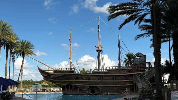 A ship-shaped pool with palm trees and a clear sky. - Disney Resort Escape w/ Pirate Pool & Spa Sleep 6 (Orlando)