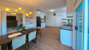 Una cucina moderna con mobili bianchi, un'area pranzo con tavolo e sedie in legno e un forno integrato.
