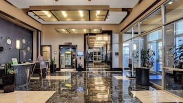 A hotel lobby with a marble floor, reception desk, and large windows.