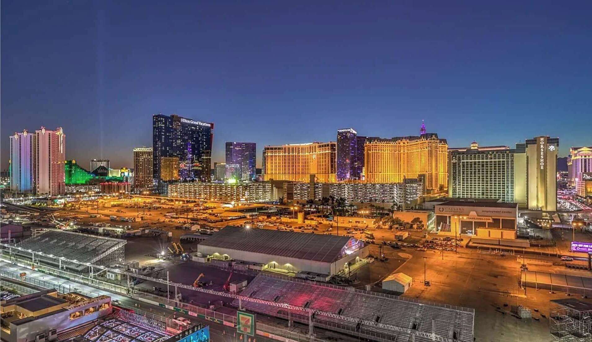 Una vista notturna di un paesaggio urbano con edifici importanti, tra cui un albergo con insegne illuminate.