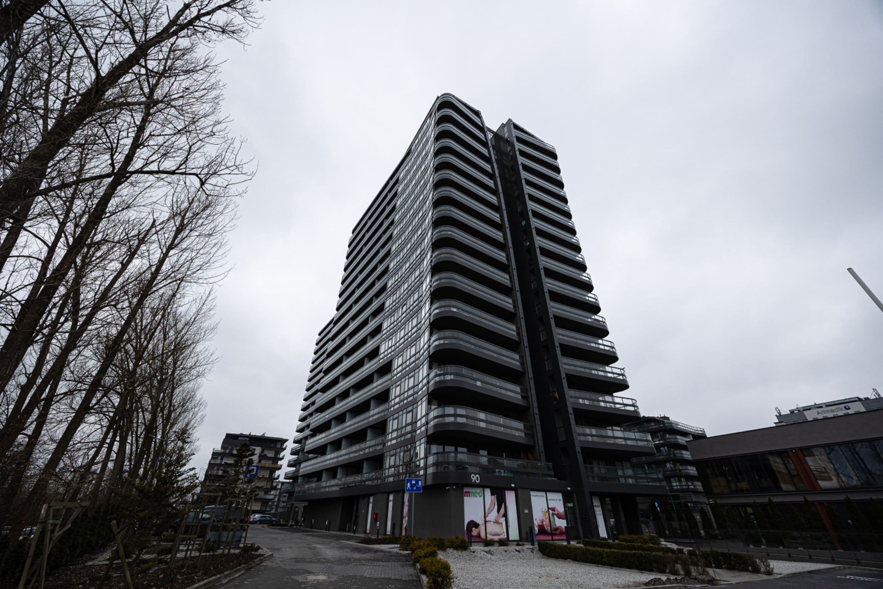 Een hoog gebouw met een modern architectonisch ontwerp, met meerdere balkons en een opvallende verticale structuur.