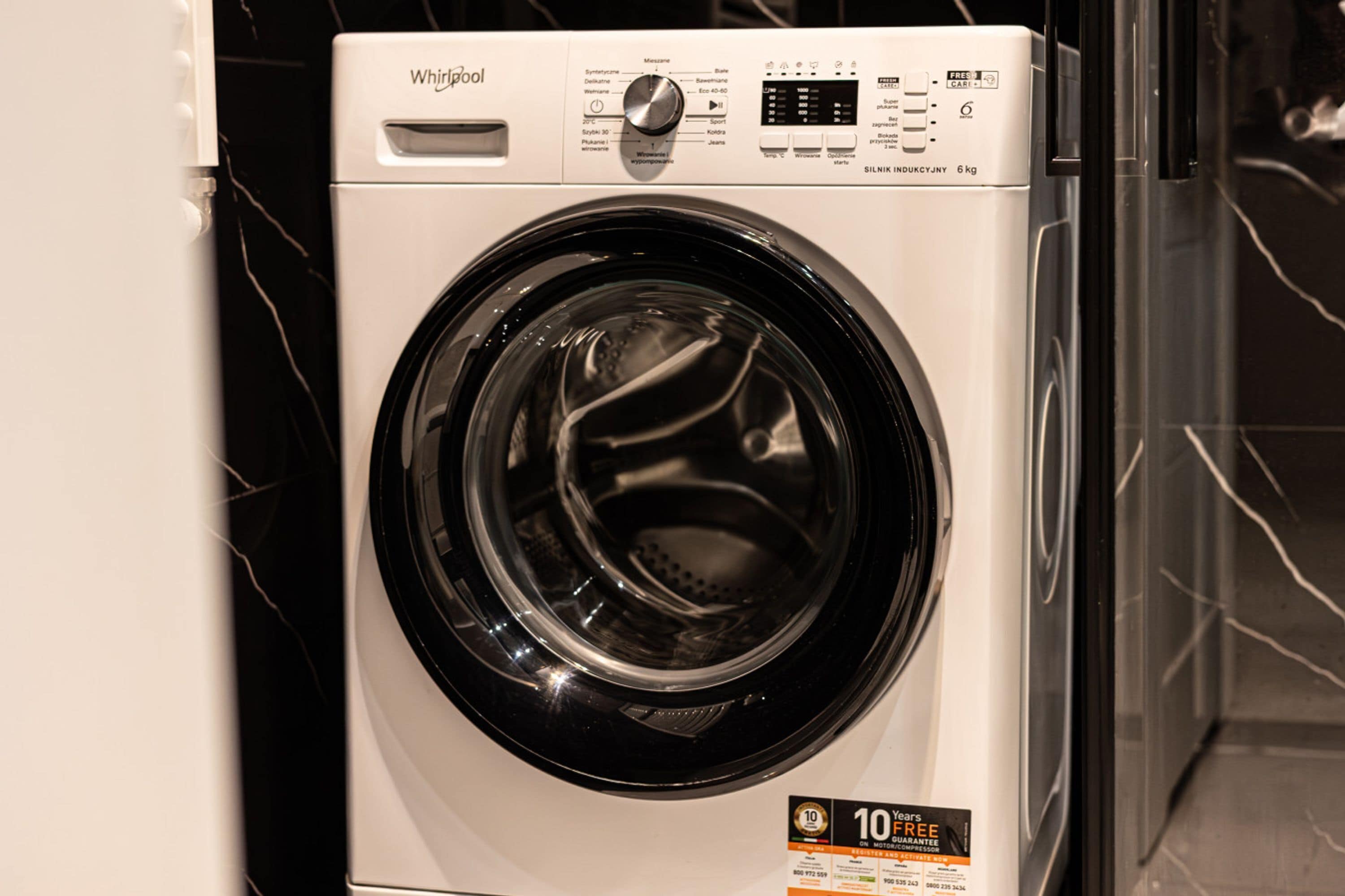 A front view of a Whirlpool washing machine with a digital control panel and a 10-year free motorcycle warranty sticker.