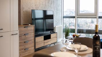 A modern kitchen with a built-in TV, wooden cabinetry, and a dining area with a table set for two.