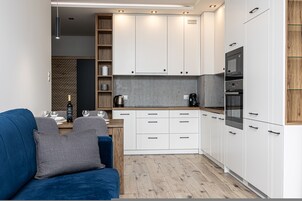 Una cocina moderna con gabinetes blancos, horno empotrado y cafetera.