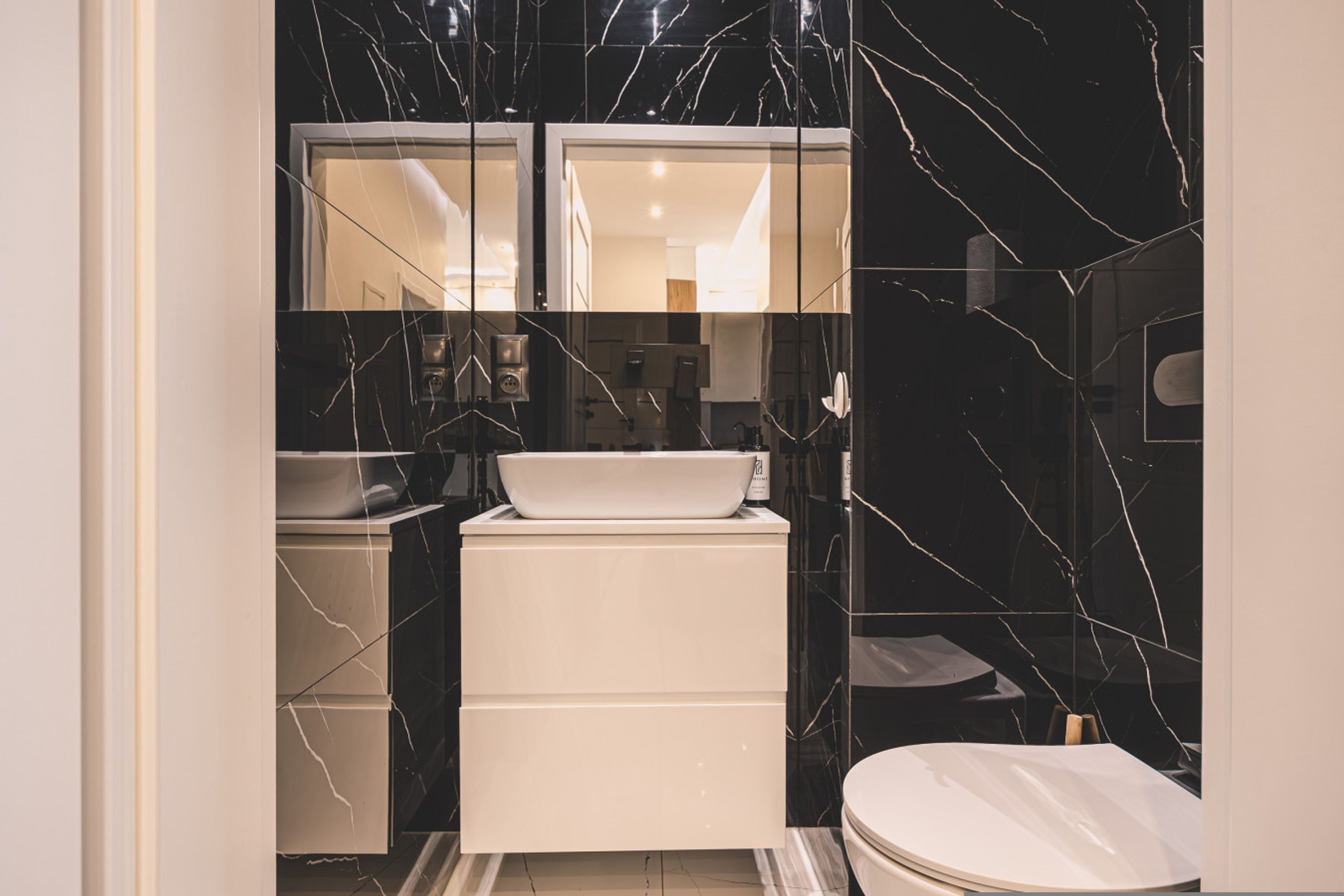 A compact bathroom with a white sink, a toilet, and a mirror above the sink.