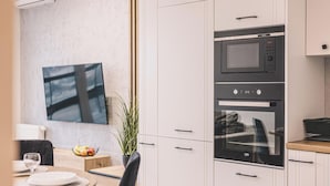 Una cocina moderna con microondas y horno integrados, una zona de comedor con mesa y sillas, y una planta en maceta.