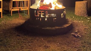 Een kampvuur met een bord waarop staat: 'Het leven is beter op de camping'.