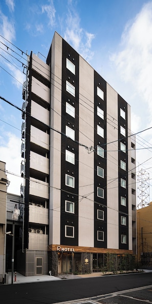A modern hotel building with multiple floors, large windows, and a visible entrance. - R Hotel Namba East (Osaka)