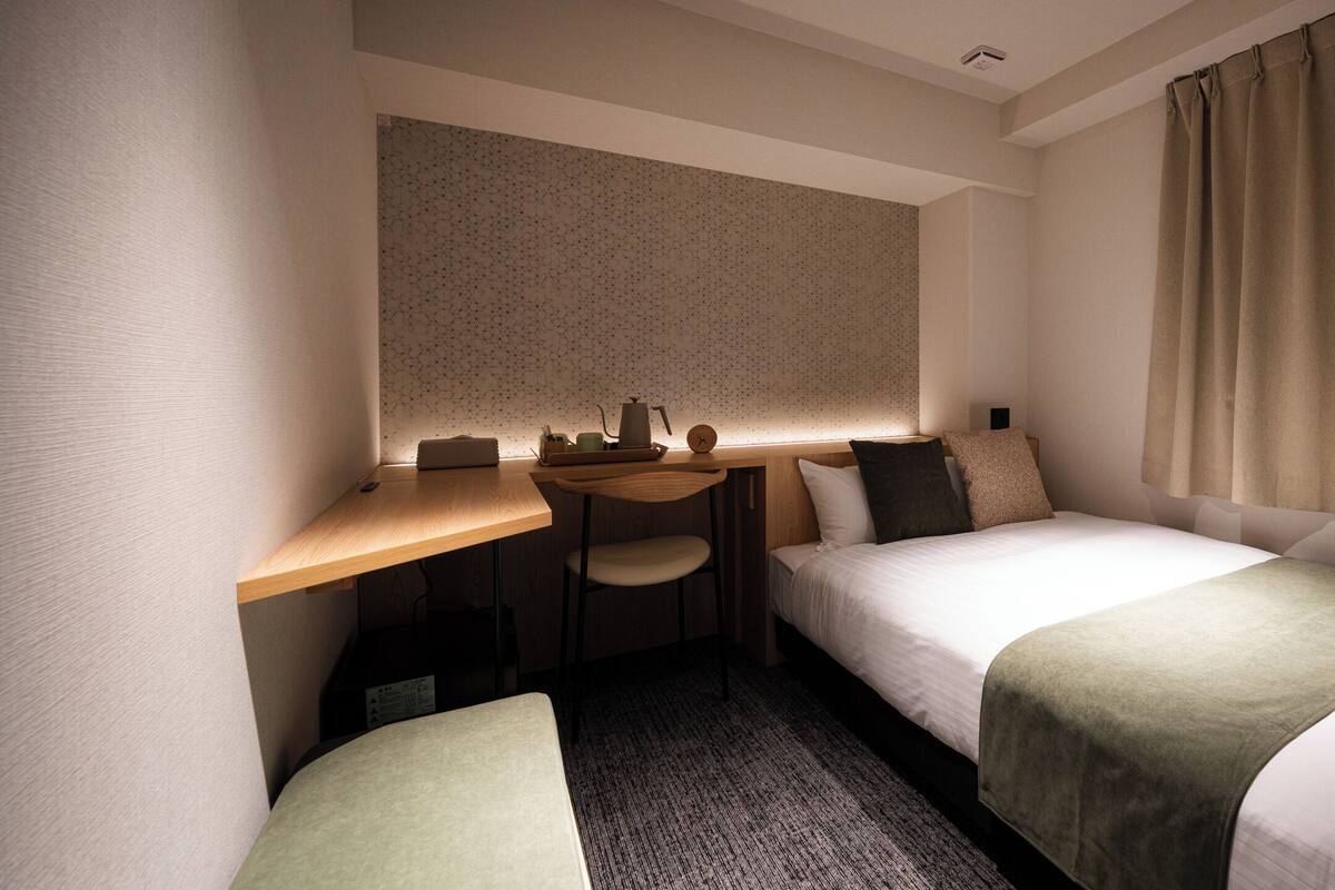 A hotel room with a bed, a desk, and a chair.