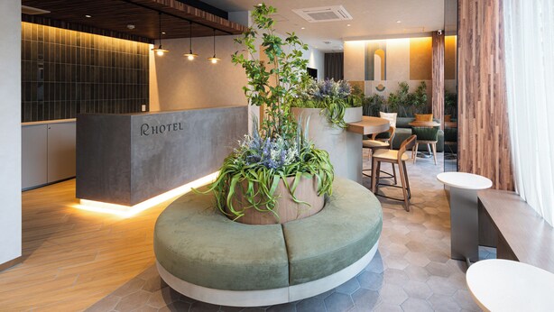 A modern hotel lobby with a reception desk, seating area, and potted plants. - R Hotel Namba East (Osaka)