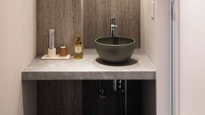 A modern bathroom with a round mirror, a vessel sink, and a light fixture above the mirror. - R Hotel Namba East (Osaka)