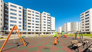 Ein Spielplatz mit Schaukeln und Rutschen, umgeben von Wohnhäusern.