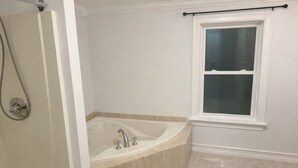 A bathroom with a bathtub, a shower, and a window. - Adorable 4-bedroom house with AC in charming Attleboro (Attleboro)