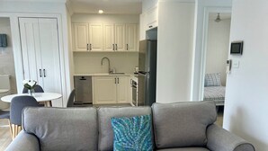 Ein modernes Wohnzimmer mit grauem Sofa, weißem Couchtisch und einem gemusterten Zierkissen.