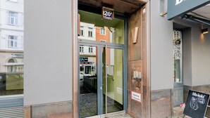 Une entrée d’immeuble avec une porte en verre, une affiche indiquant une réduction de 20 %, et une enseigne pour « fittz-kola » accompagnée d’un slogan.