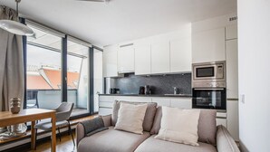 Un salon moderne comprenant un canapé, une table à manger et un coin cuisine équipé d’appareils électroménagers.
