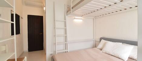 A bedroom with a bunk bed, a desk, and a ladder.