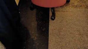 Ein kleiner Büroraum mit einem weißen Marmortisch, einem roten Bürostuhl und einer gelben Wand.