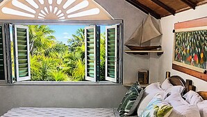 Ein Schlafzimmer mit Bett, einem Fenster mit Rollläden, einem Deckenventilator und einem Bild an der Wand.