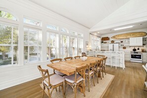A spacious kitchen with a wooden table and chairs, white cabinetry, and large windows. - 🏖️ Coastal Decor | Pool | Bikes | Ping-Pong Table 🏓 (Seagrove)