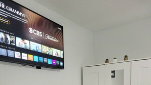 A room with a flat-screen TV mounted on the wall displaying various streaming services. There is a white wardrobe with a mirror and a small potted plant on top. - Private Suite Independent Entrance, All Amenities (Kissimmee)