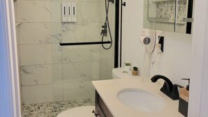A modern bathroom with a glass-enclosed shower, a white toilet, and a vanity with a sink. - Private Suite Independent Entrance, All Amenities (Kissimmee)