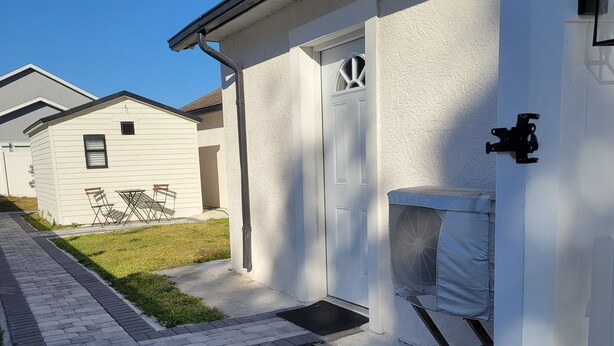 A residential building with a paved walkway, a door, and a window. - Private Suite Independent Entrance, All Amenities (Kissimmee)