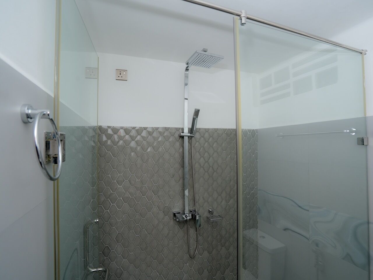 A glass-enclosed shower with a modern design, featuring a rain shower head and a handheld shower attachment.