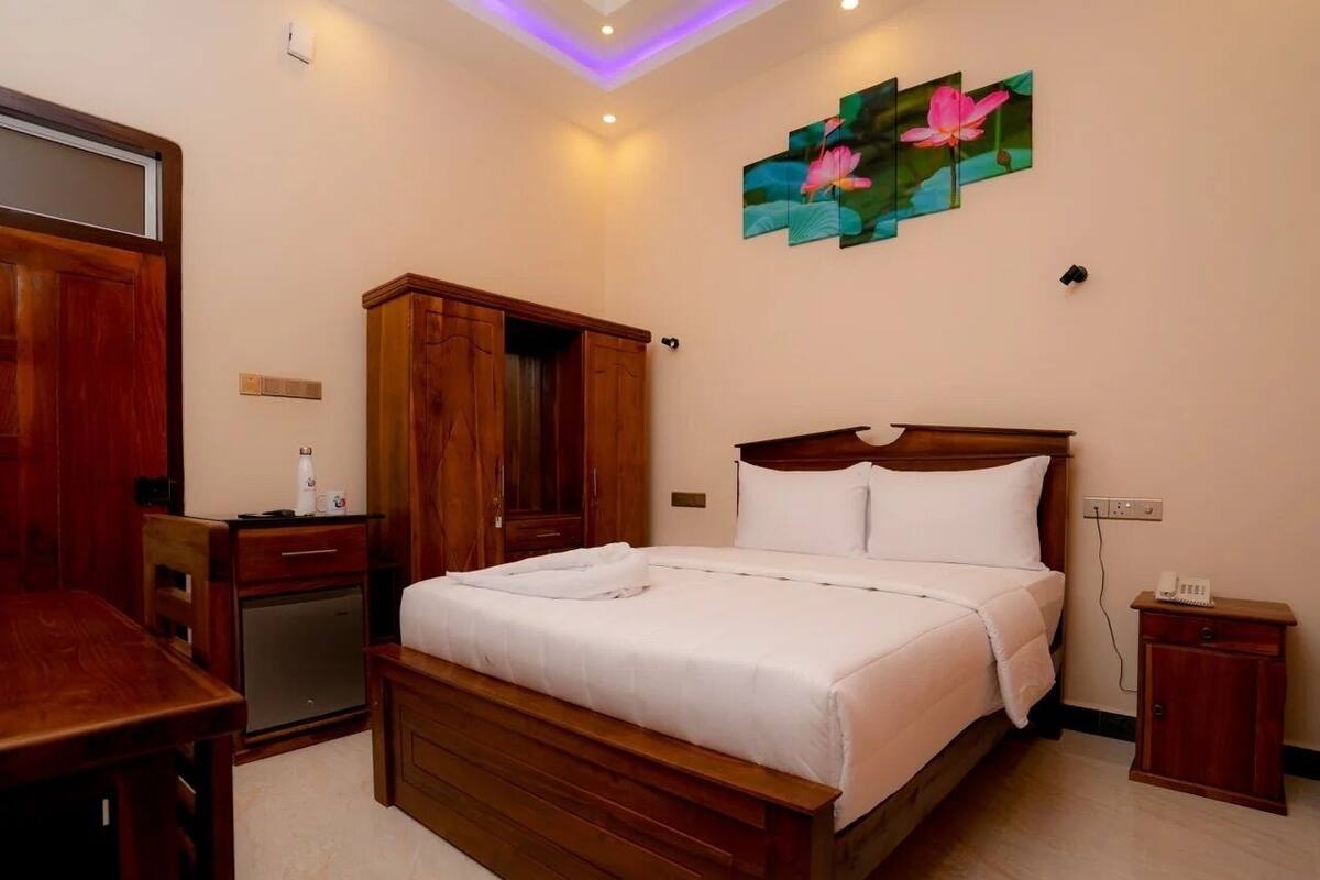 A bedroom with a wooden bed, a desk, a wardrobe, and a small bedside table.