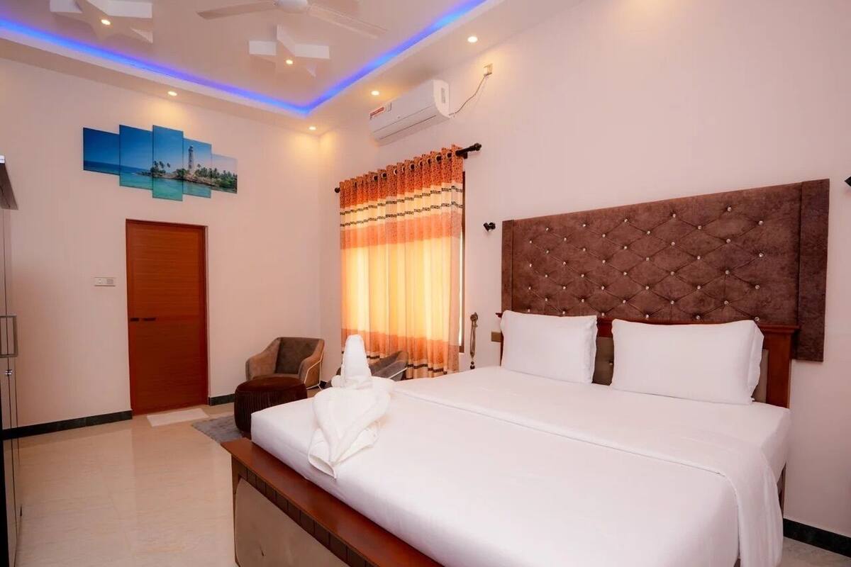 A hotel room with a large bed, a wooden headboard, a desk, and a chair.