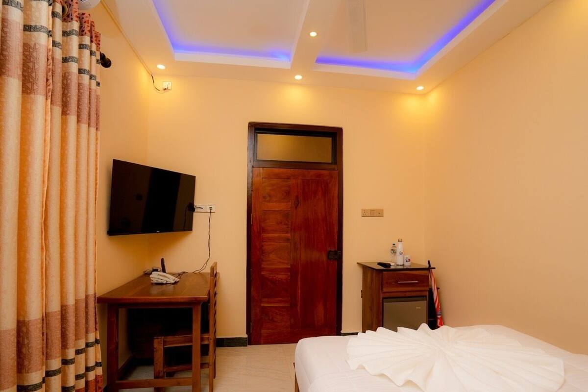 A hotel room with a bed, a desk, a television, and a door.