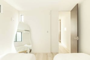 Ein modernes Hotelzimmer mit einem großen Spiegel, einem Bett, einem Kleiderschrank und einem kleinen Fenster.