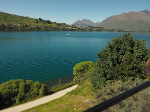 Ein See mit einer Straße, die zu einem Dorf führt, umgeben von Bergen.