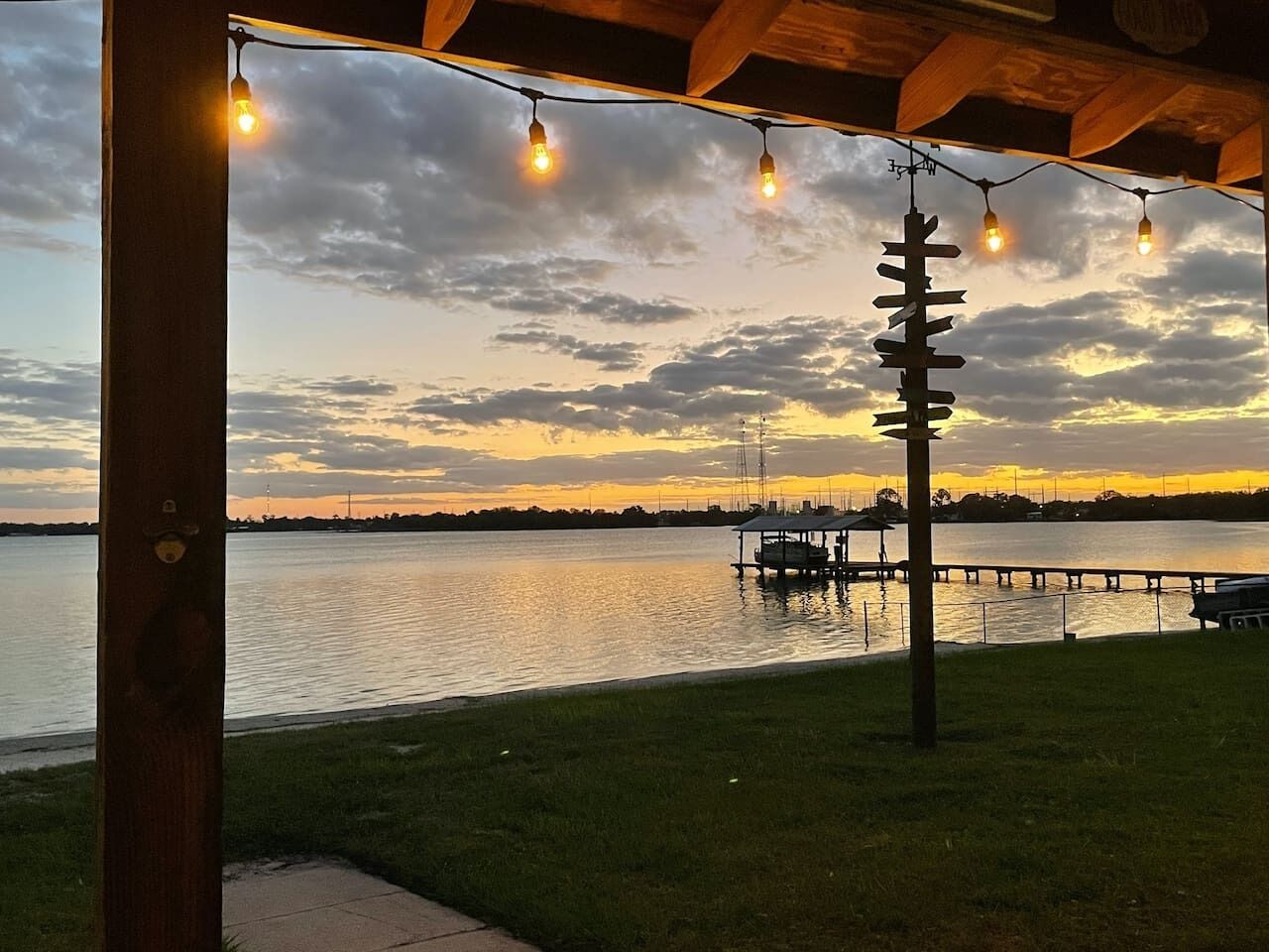 A waterfront view with a dock and a gazebo with string lights.