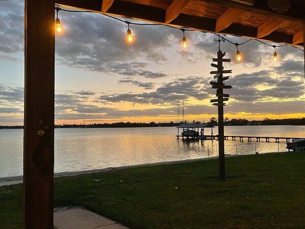 A waterfront view with a dock and a gazebo with string lights.