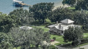 Une maison avec une jetée qui s’avance sur un plan d’eau, entourée d’arbres.