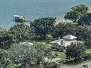 A house with a dock extending into a body of water, surrounded by trees.