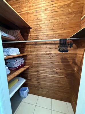 Un armario de madera con repisas que sostienen toallas dobladas y una barra para colgar ropa.