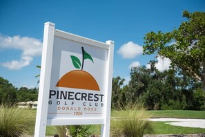 A sign for Pinecrest Golf Club with a logo featuring a stylized sun and leaves, and the name 'Donald Ross 1926' below.