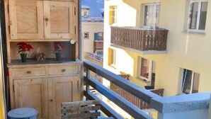 A balcony with a wooden bench, a small table, and a trash bin. - Derby 31 by Interhome (St. Moritz)